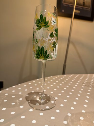 Champagne flute with floral and leaf designs on a polka dot tablecloth.
