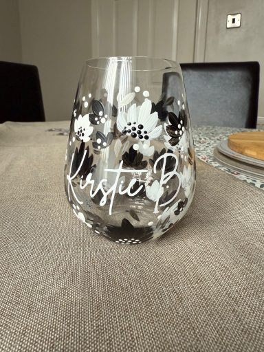 A decorative glass with white floral patterns and the name "Veronica B" inscribed.