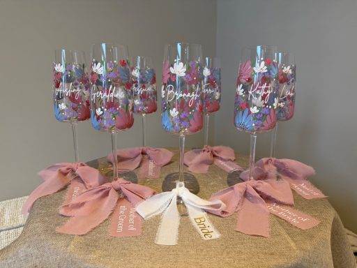 Decorative glasses with colourful designs, arranged on a table with pink ribbons.