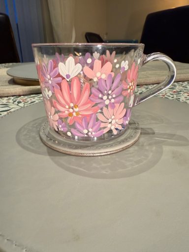 A decorative glass teacup with pink and purple flower designs.