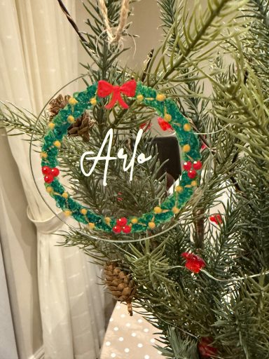 A festive green wreath ornament with red bows and "Ava" written in white.