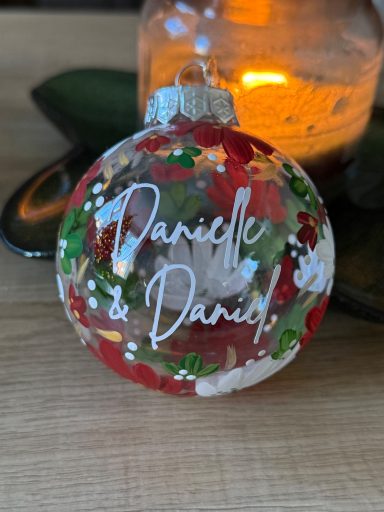 Clear Christmas bauble filled with red, green, and white decorations, personalised with "Danielle & Daniel".