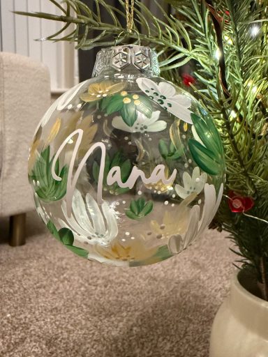 A decorative glass ornament with the name "Nana" and floral designs.